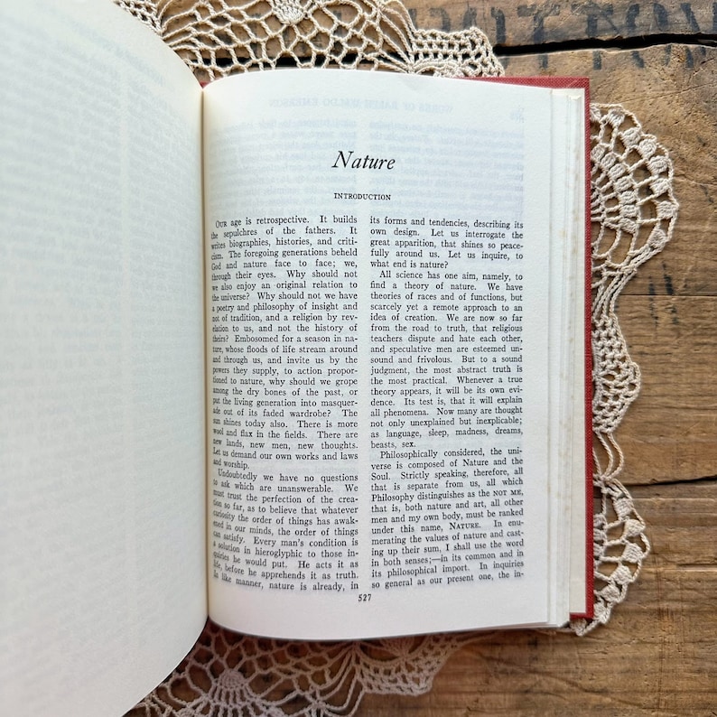 May include: A vintage book with a red cover and gold lettering. The title of the book is "Nature" and the text on the page discusses the concept of nature and its relationship to humanity.
