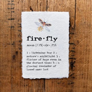 Może przedstawiać: Biała kartka z napisem "firefly" i jego definicją, wraz z akwarelową ilustracją świetlika. Definicja zawiera terminy "lightning bug", "nature's nightlight" i "glowing reminder of loved ones lost."