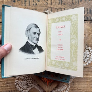 May include: A vintage book titled "Essays: First Series" by Ralph Waldo Emerson, published by Henry Altemus in Philadelphia. The cover features a portrait of Emerson and an ornate floral design.