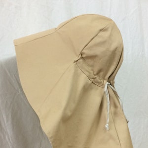 Puede incluir: Un sombrero de sol de color beige con un ala ancha y un cierre de cordón. El sombrero está hecho de una tela suave y ligera.