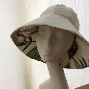 Puede incluir: Un sombrero de sol blanco con un forro de estampado tropical. El sombrero est&aacute; hecho de una tela suave y ligera y tiene un ala ancha.