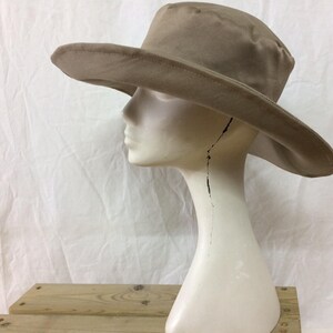 May include: A wide-brimmed, tan-colored sun hat with a slightly rounded crown. The hat is made of a soft, pliable material and has a simple, classic design.