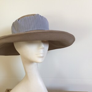 May include: A wide-brimmed sun hat with a tan fabric crown and a black and white striped fabric band.