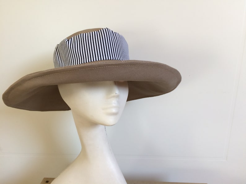 May include: A wide-brimmed sun hat with a tan fabric crown and a black and white striped fabric band.
