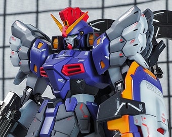 May include: A detailed model of a blue and white robot with orange and yellow accents. The robot has a large, black, curved tail and is holding a gun in its left hand.