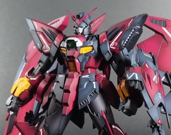 May include: A detailed model of a mecha robot, primarily in shades of red, black, and gray. The robot features large, wing-like structures on its back and a segmented tail. Yellow accents are visible on the shoulders and other parts of the body.