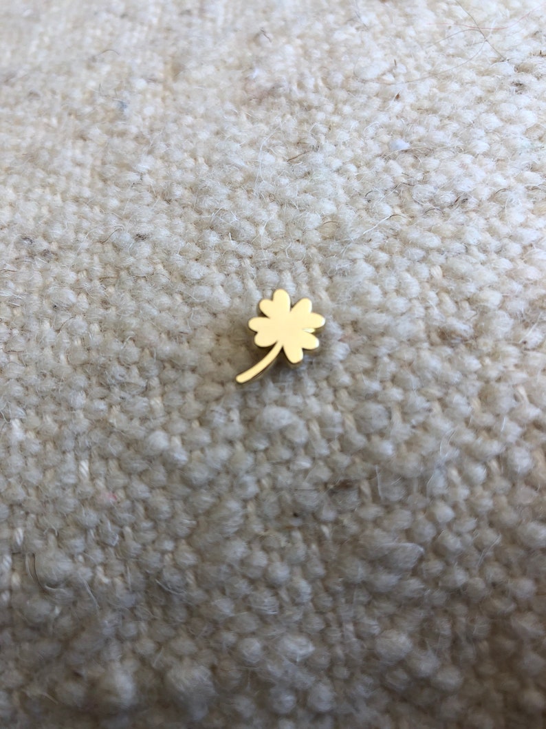 May include: A gold four-leaf clover charm.