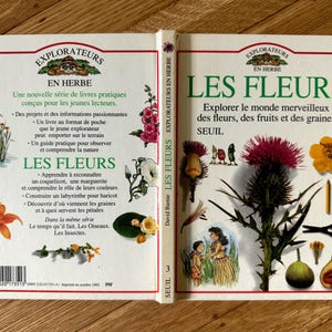 May include: A book titled "LES FLEURS" with the text "Explore the wonderful world of flowers, fruits and seeds." The cover features illustrations of flowers, fruits, and gardening tools. The book is part of the "EXPLORATEURS EN HERBE" series.