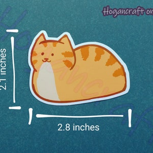 Puede incluir: Pegatina de gato de dibujos animados naranja y blanco, de 2,8 pulgadas de ancho y 2,1 pulgadas de alto. El gato est&aacute; tumbado de lado con las patas metidas debajo del cuerpo.