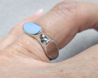 May include: A silver ring with a light blue oval-shaped stone set in the center.