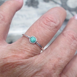 May include: A silver ring with a small, round turquoise stone.