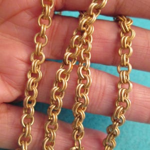 May include: A gold chain necklace with a twisted rope design. The chain is made of multiple strands of gold wire that are twisted together to create a rope-like effect.