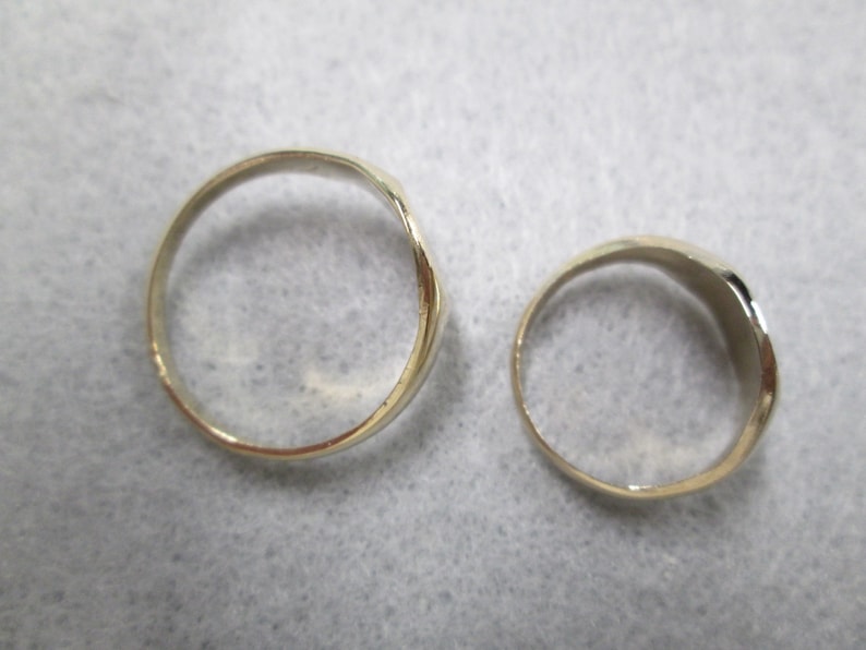 May include: Two gold-colored rings, one is wider than the other, both are smooth and shiny.