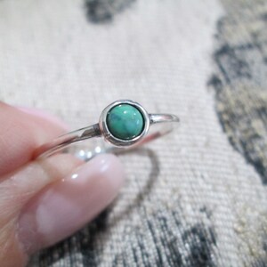 May include: A silver ring with a small, round, green gemstone.