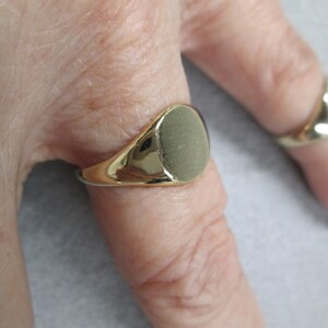May include: A gold signet ring with a smooth, oval-shaped top.