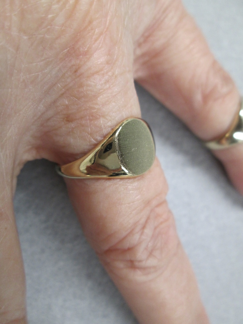 May include: A gold signet ring with a smooth, oval-shaped top.