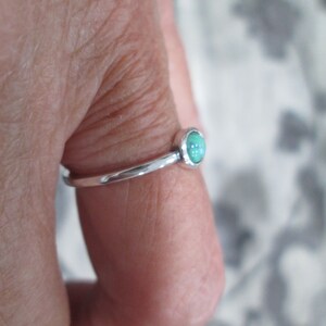 May include: A silver ring with a light green oval gemstone.