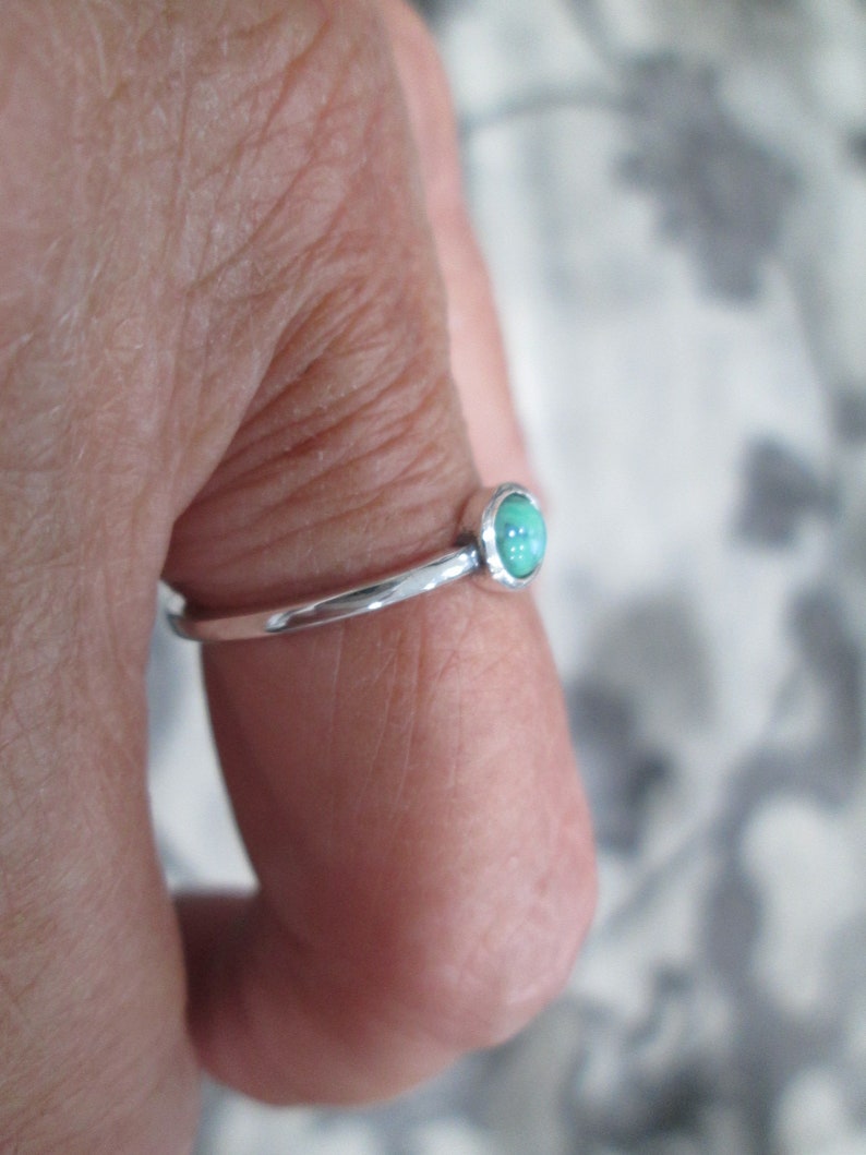 May include: A silver ring with a light green oval gemstone.