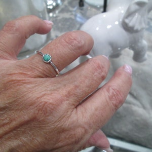 May include: A silver ring with a small, round turquoise stone set in the center.