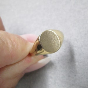 May include: A gold signet ring with a smooth, oval-shaped top.