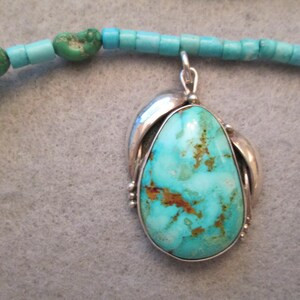Peut inclure: Un collier avec un pendentif en turquoise serti d'argent. Le pendentif est en forme de larme avec une pierre turquoise bleue et verte. Le collier est compos&eacute; de perles turquoise.