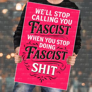 May include: A pink poster with the text "WE'LL STOP CALLING YOU FASCIST WHEN YOU STOP DOING FASCIST SHIT" in white and black. The poster is held by a person.