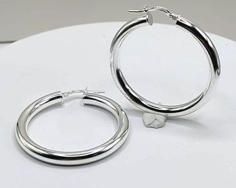 May include: A pair of silver hoop earrings. The hoops are thick and round, and they have a polished finish.