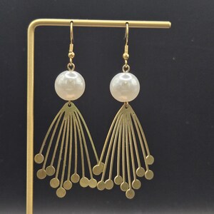 May include: Gold tone earrings with a white pearl and a geometric design.