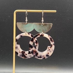 May include: A pair of dangle earrings with a tortoiseshell pattern and a light blue and gold half-circle accent.