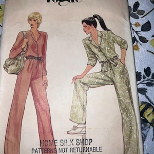 May include: A Vogue sewing pattern envelope, number 8011, size 14, featuring illustrations of two jumpsuits. One is solid mauve with a belt and shoulder bag, the other is light green with a white floral print, a collared neckline, and a tie waist.