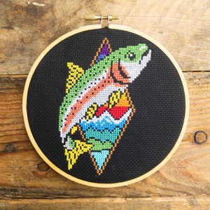 May include: A rainbow-colored fish cross-stitch embroidery design on black fabric, framed in a wooden hoop.
