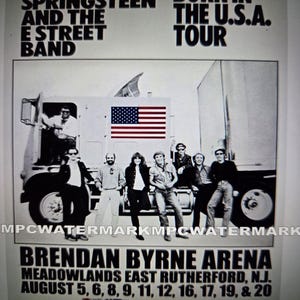 May include: A black and white concert poster for Bruce Springsteen and the E Street Band's "Born in the U.S.A." tour. The poster features a group of musicians in front of a truck with an American flag. The poster also lists the venue and dates.
