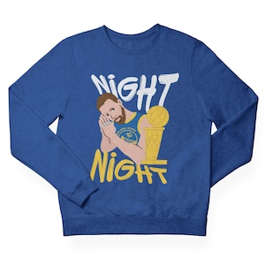 May include: A royal blue sweatshirt with a white graphic of a basketball player holding a championship trophy. The graphic includes the text "NIGHT NIGHT".