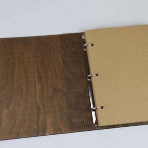 May include: A brown wooden binder with a ring mechanism and a blank brown paper page.