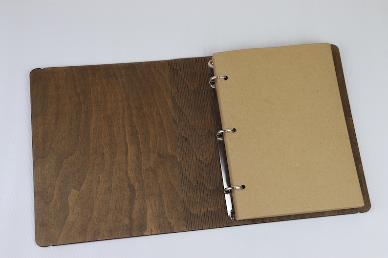 May include: A brown wooden binder with a ring mechanism and a blank brown paper page.