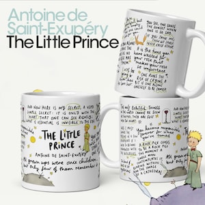 May include: White ceramic mug with a black handle featuring a quote from Antoine de Saint-Exupéry's "The Little Prince" with illustrations of the Little Prince and a fox. The quote reads: "And now here is my secret, a very simple secret: It is only with the heart that one can see rightly; what is essential is invisible to the eye."