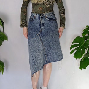 Peut inclure: Une femme porte une chemise à manches longues à motif vert et marron avec un col en V et une jupe en jean bleu à ourlet effiloché.