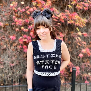 Puede incluir: Un top corto de crochet negro con ribete de crochet blanco. El top tiene el texto "RESTING BITCH FACE" escrito en blanco.