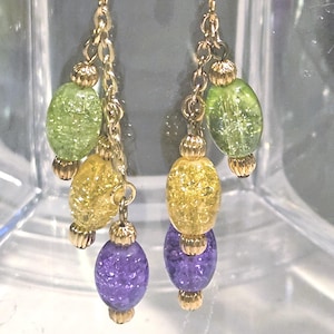 May include: Gold-tone dangle earrings with a chain design. Each earring features three colorful, textured beads: green, yellow, and purple. The earrings have a hook closure.