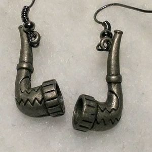 May include: A pair of silver tone earrings shaped like a pipe. The earrings have a hook closure.