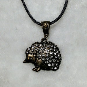May include: A silver and black necklace with a rhinestone hedgehog pendant.