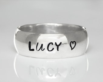 May include: A silver band ring with the name "Lucy" and a heart engraved on it.