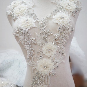 May include: White beaded and floral applique with rhinestones. This embellishment is perfect for adding a touch of elegance to wedding dresses, bridal gowns, or other formal wear.