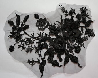 Puede incluir: Aplique de encaje floral negro con adornos de cuentas. El encaje presenta delicadas flores y hojas, y los adornos añaden un toque de brillo.