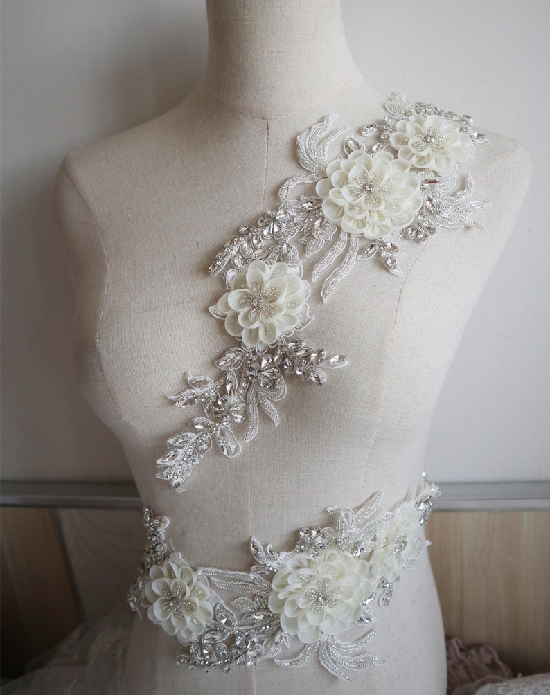 May include: White floral applique with silver beading and rhinestones. The applique is perfect for adding a touch of elegance to wedding dresses, bridal accessories, or other special occasion garments.