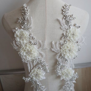 May include: Two white floral appliques with silver rhinestone embellishments. The appliques are on a white mannequin.