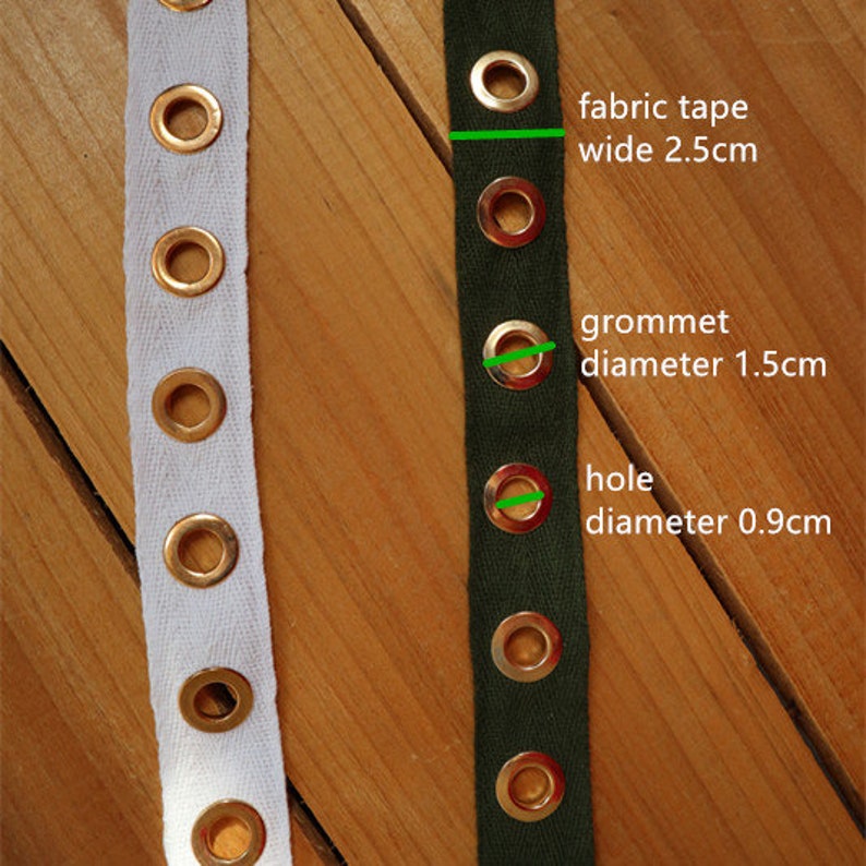 May include: Close-up of two fabric tapes with metal grommets. One tape is white, the other is dark green. The green tape has text indicating the fabric tape is 2.5cm wide, grommet diameter is 1.5cm, and hole diameter is 0.9cm.