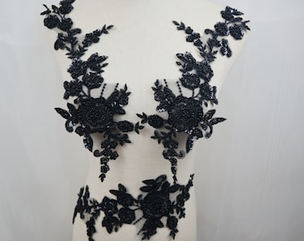 May include: Black floral lace applique with sequins. The applique is in the shape of a flower and has a delicate design. It is perfect for adding a touch of elegance to any garment.