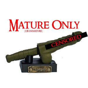 May include: An olive green novelty item shaped like a phallus, mounted on a black base with a gold-colored nameplate that reads "Thompson". The text "MATURE ONLY (OR IMMATURE)" is above the item, and the word "CENSORED" is across the head.