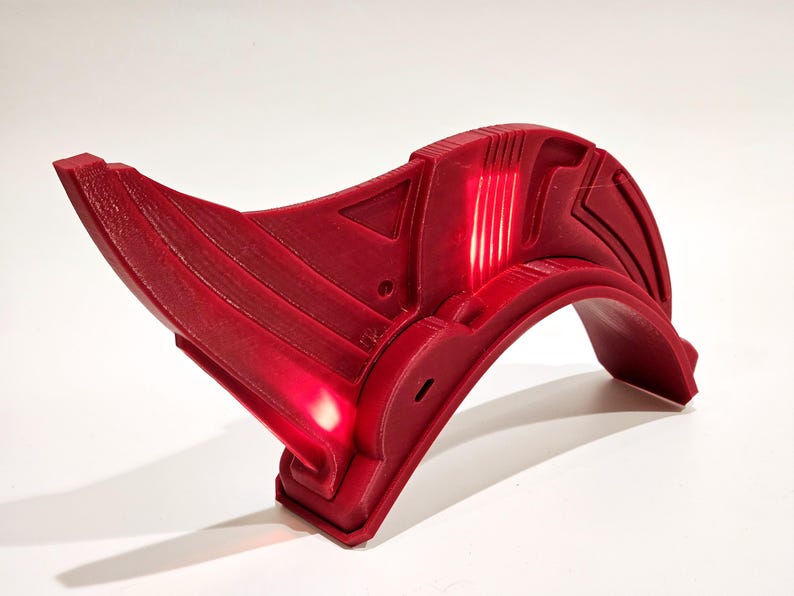Op de afbeelding: Een rode helm van 3D-geprint plastic met een gebogen ontwerp en een licht erin.